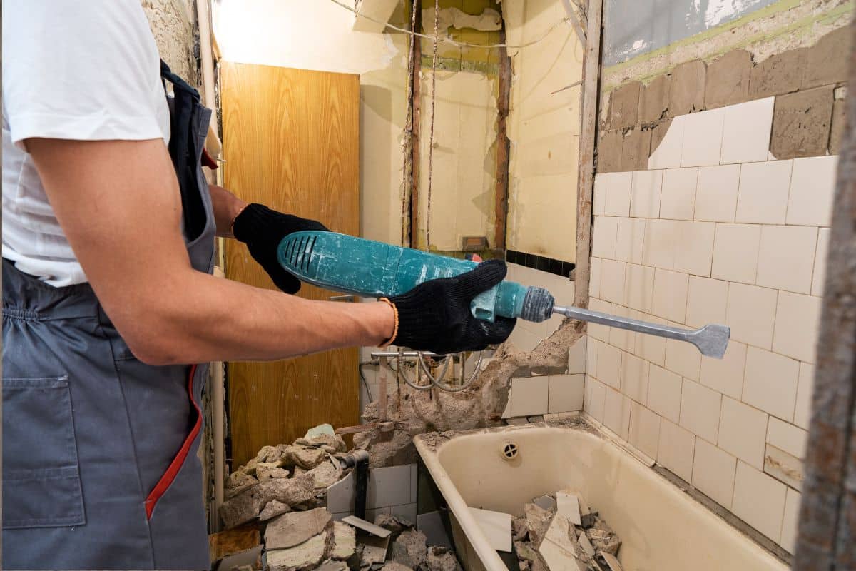 Un homme utilise un outil pour rénover une salle de bain.