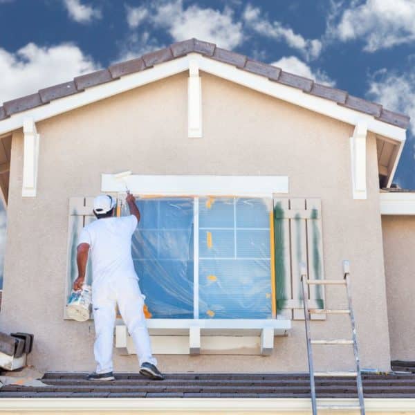 Un peintre réalisant une rénovation immobilière en peignant une maison.