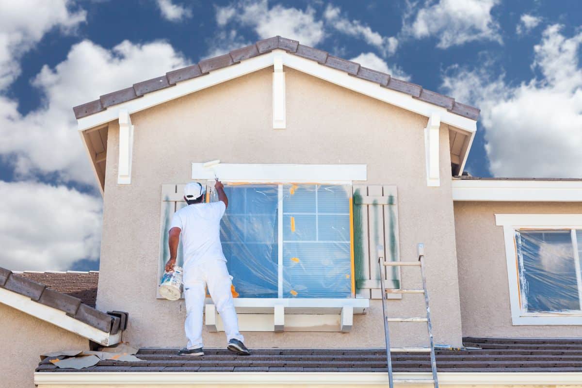 Un peintre réalisant une rénovation immobilière en peignant une maison.
