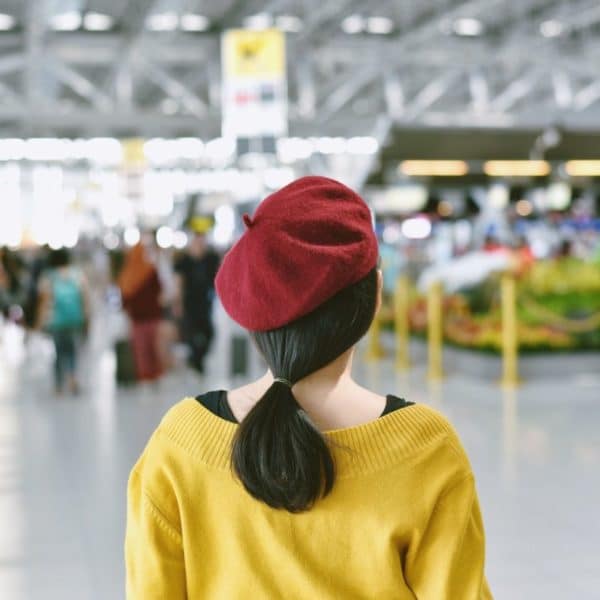 Une Femme Portant Un Béret Rouge Se Tient Dans Un Aéroport.