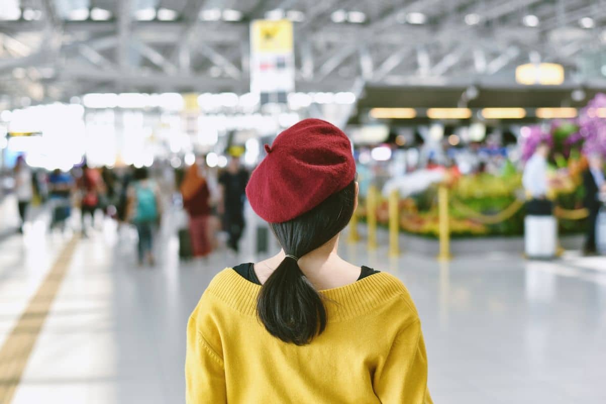 Une Femme Portant Un Béret Rouge Se Tient Dans Un Aéroport.