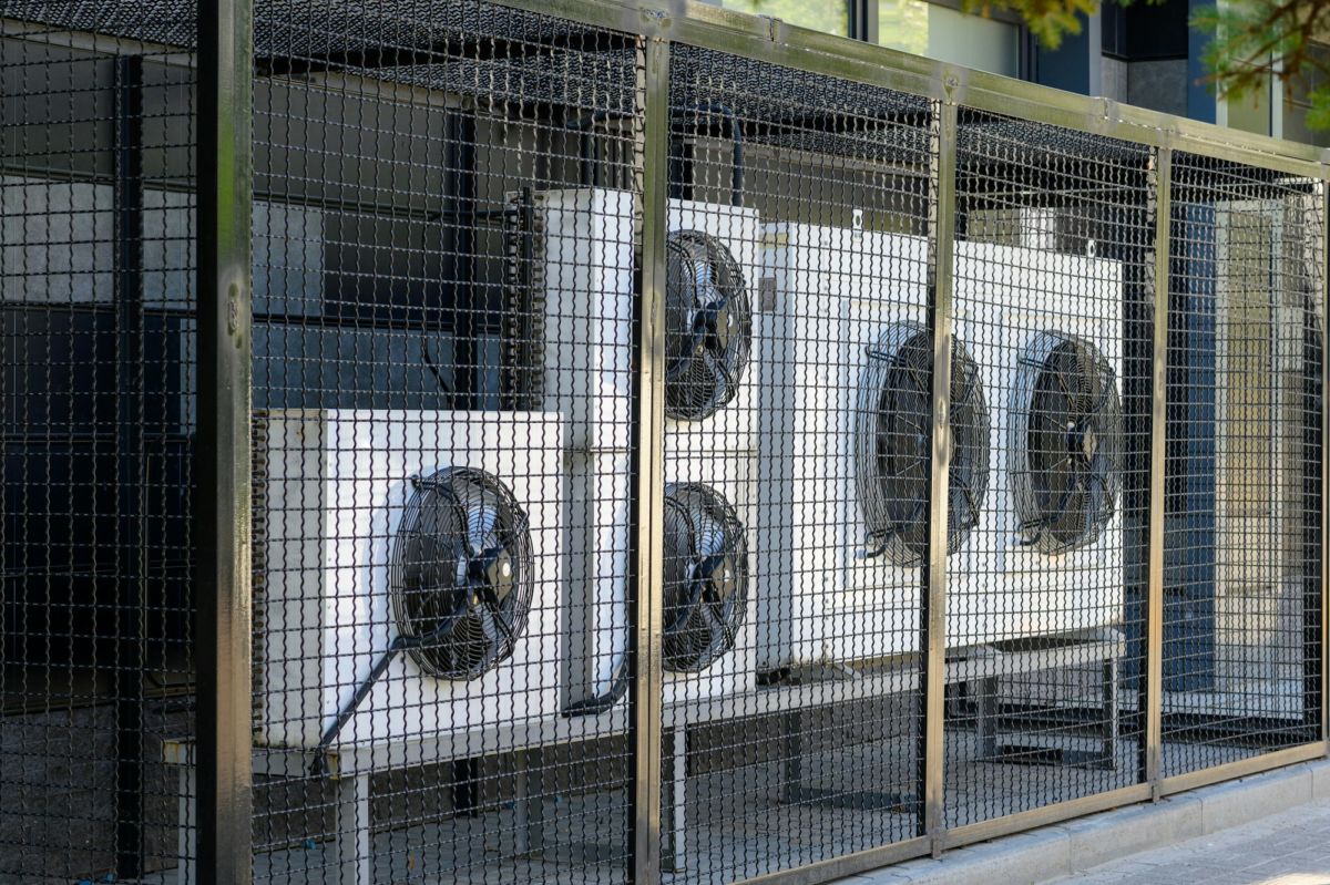 Le système de compression et de climatisation d'un bâtiment protégé par une clôture métallique.