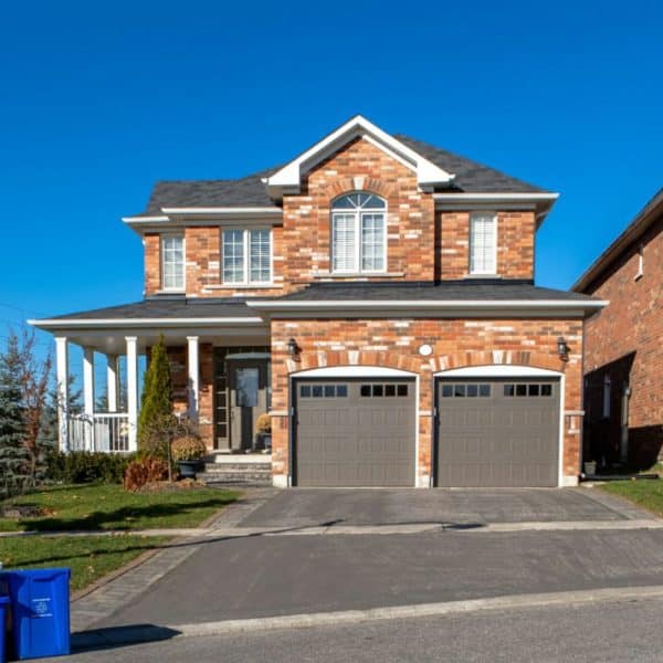 Une Maison Avec Deux Garages Et Une Poubelle.