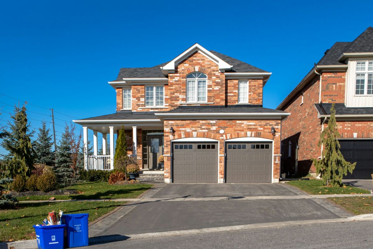 Une Maison Avec Deux Garages Et Une Poubelle.