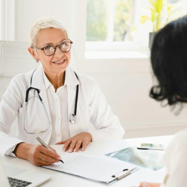 Un Médecin Parle à Un Patient Assis à Un Bureau.