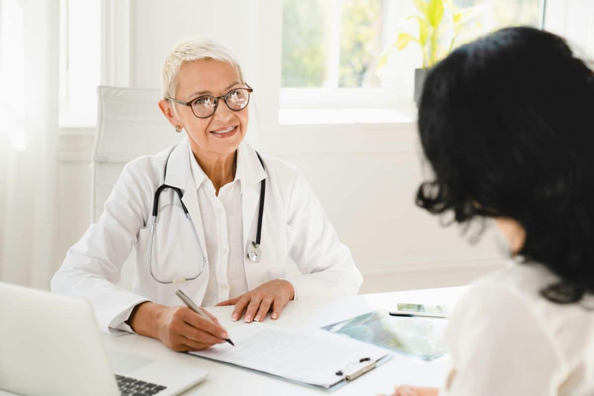 Un Médecin Parle à Un Patient Assis à Un Bureau.