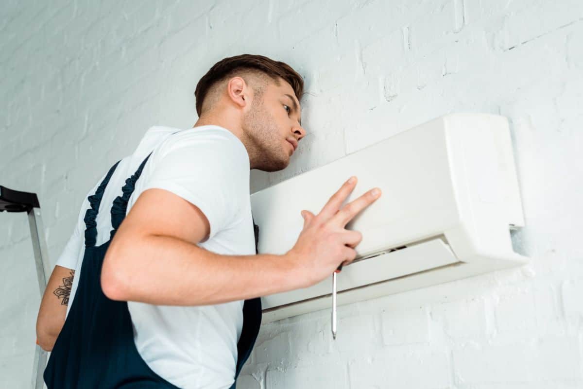 Un professionnel installant un climatiseur dans une maison.