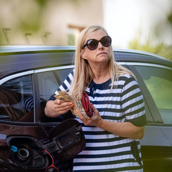 worried woman with cash at the car, put money to car tank, the concept of rising fuel prices