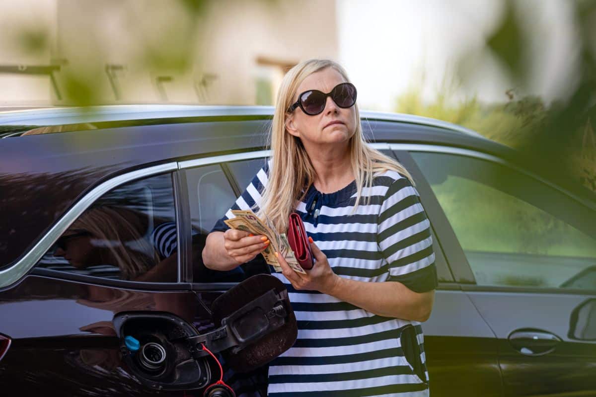 worried woman with cash at the car, put money to car tank, the concept of rising fuel prices