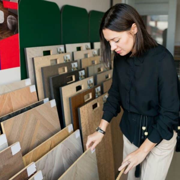 Young woman choosing materials for home renovation. interior designer examining wood samples floor