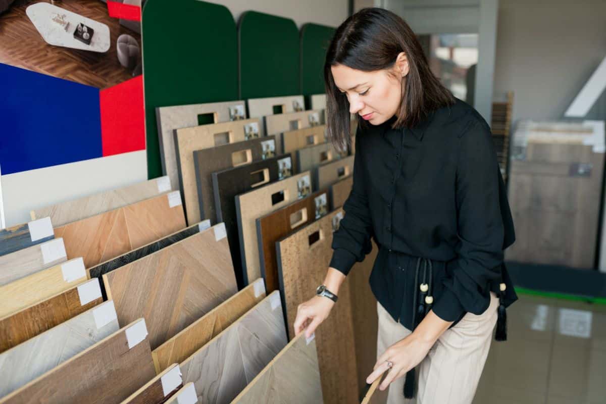 Young woman choosing materials for home renovation. interior designer examining wood samples floor