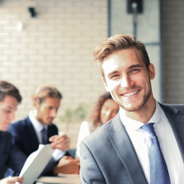 Homme d'affaires souriant avec des collègues en arrière-plan.