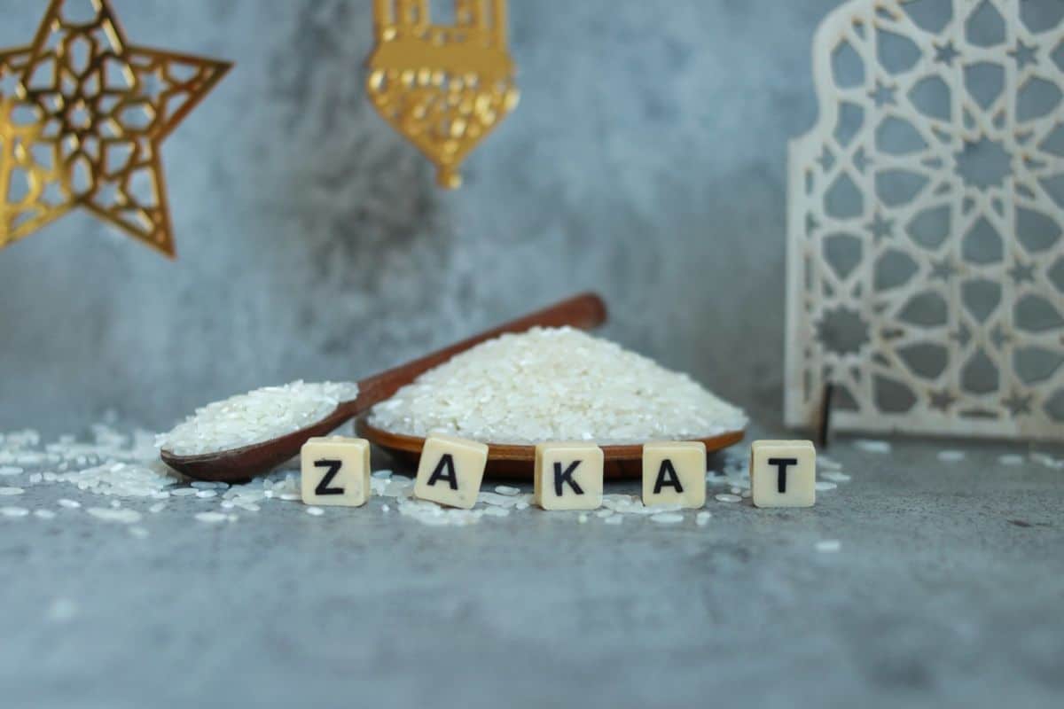 Le mot zakat est écrit sur une planche de bois à côté d’un bol de riz.