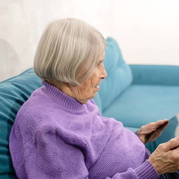 Une Femme âgée Assise Sur Un Canapé à L’aide D’une Tablette.