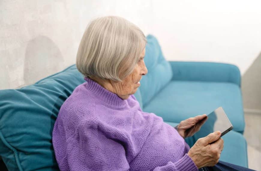 Une Femme âgée Assise Sur Un Canapé à L’aide D’une Tablette.