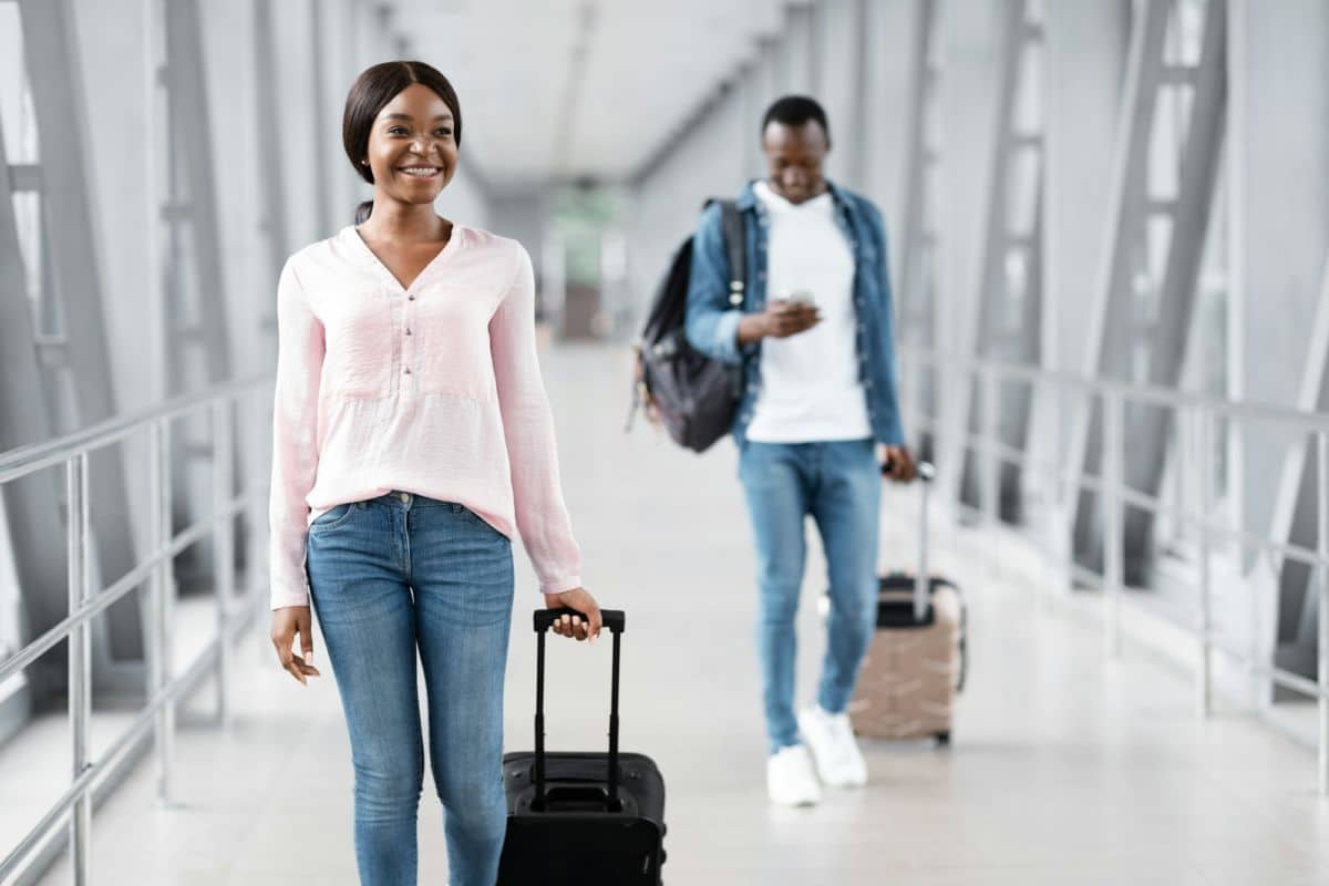 Une Femme Souriante Avec Des Bagages Dans Un Couloir.