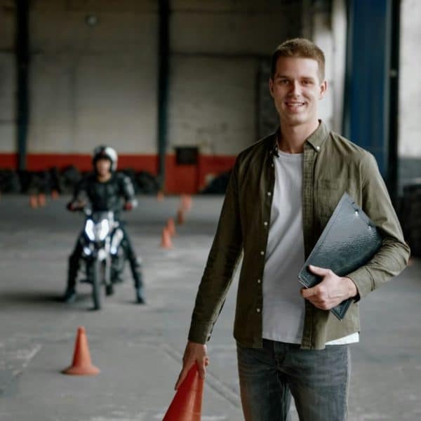 Portrait d'un instructeur d'auto-école souriant et heureux lors d'un entraînement au motodrome