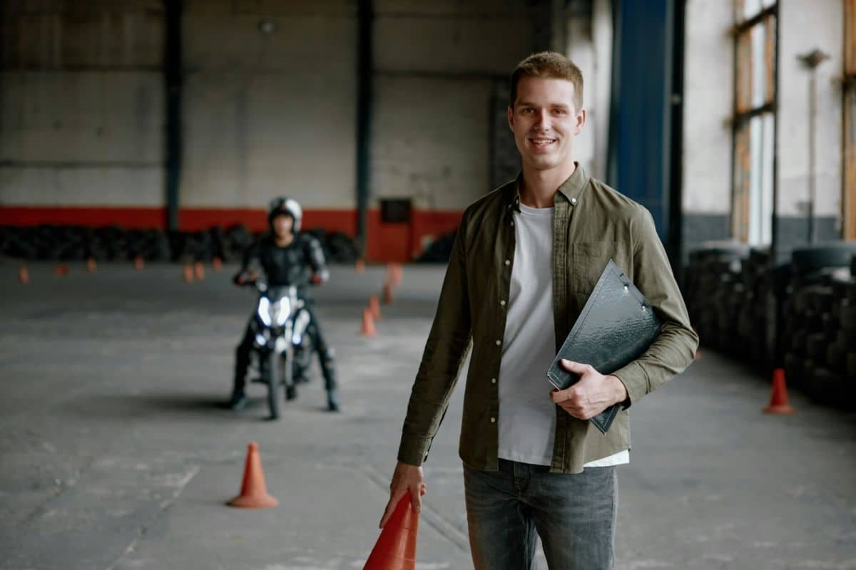 Portrait d'un instructeur d'auto-école souriant et heureux lors d'un entraînement au motodrome