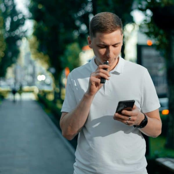 Un homme fume une cigarette électrique dans la rue