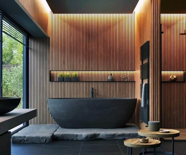 Salle de bains moderne avec boiseries murales, baignoire autoportante noire, miroir circulaire et grandes fenêtres. Cette chambre dispose de plantes d'intérieur, d'un espace douche et d'une décoration minimaliste.