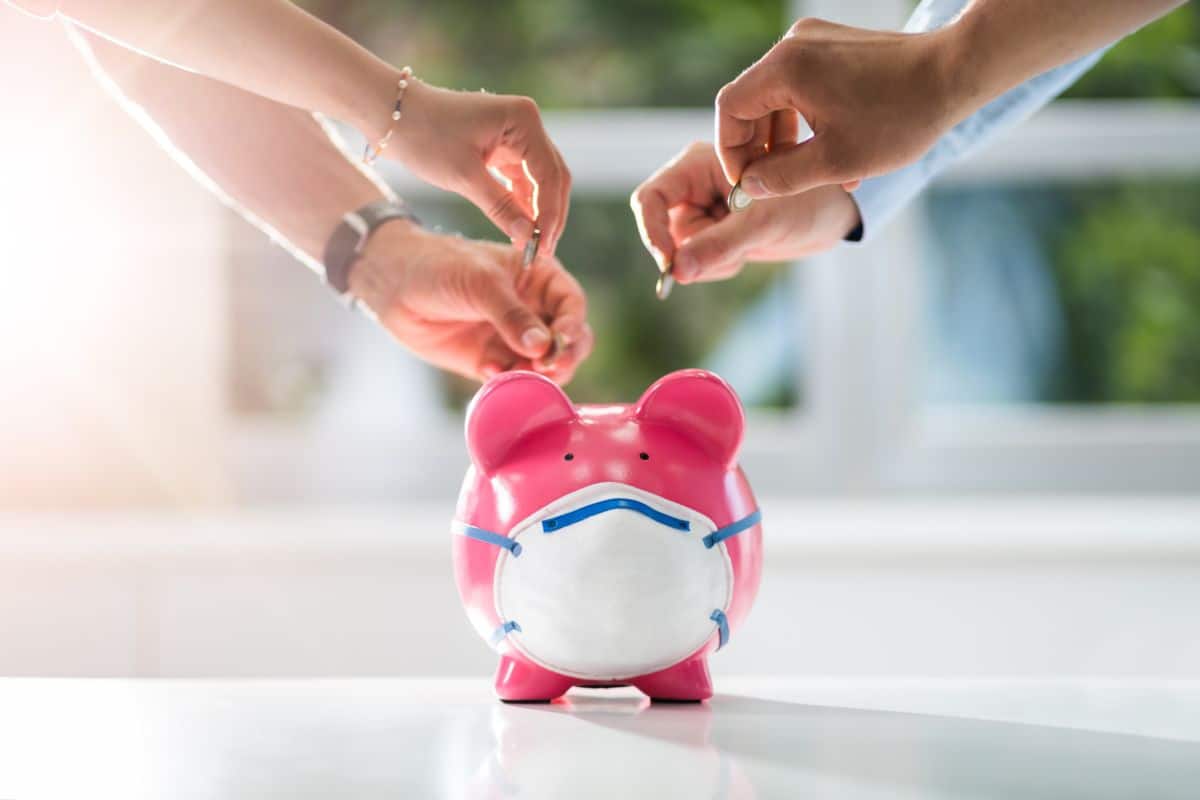Mains Déposant Des Pièces Dans Une Tirelire Rose Portant Un Masque Facial.