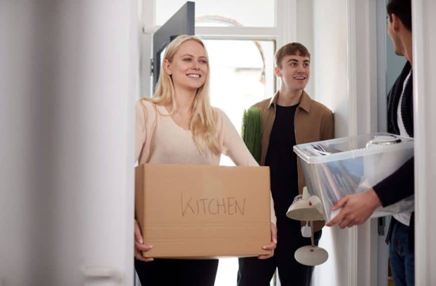 Group Of College Student Carrying Boxes Moving Into Accommodation Together