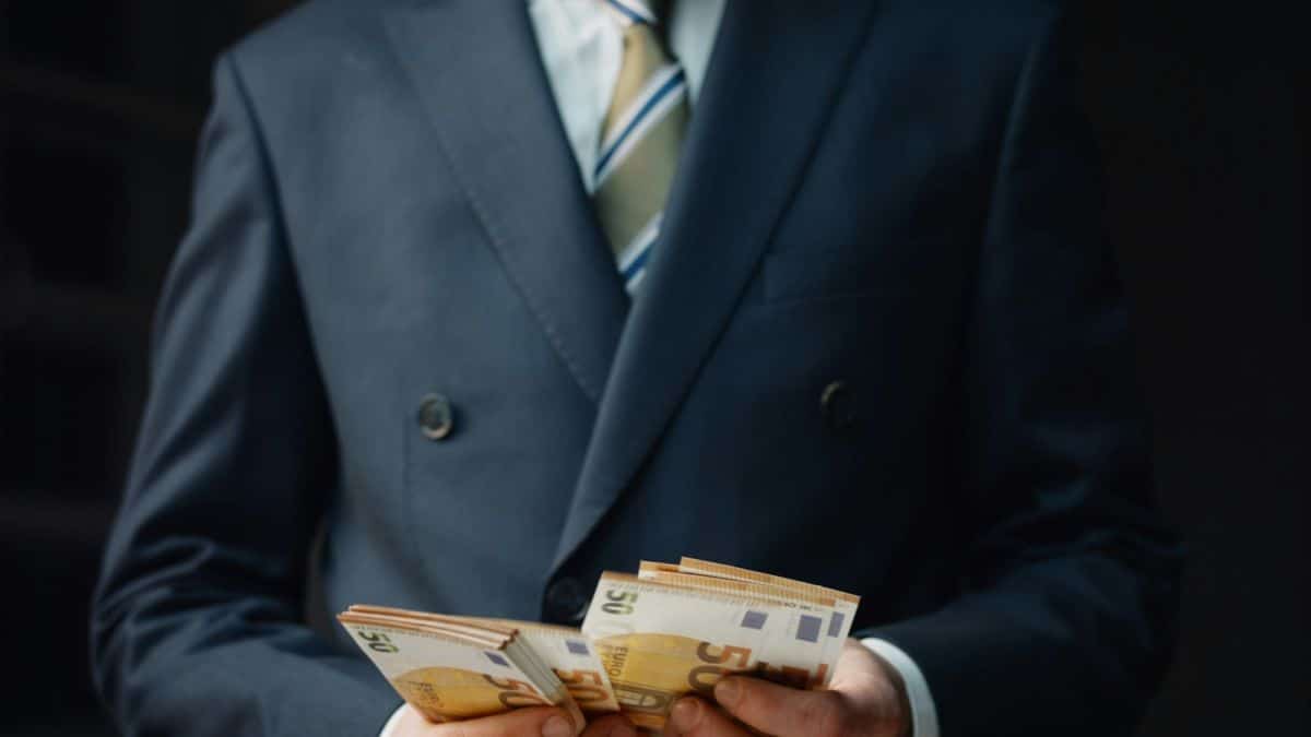 Une Personne En Costume Tient Une Pile De Billets De 50 Euros.