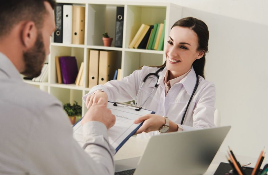 smiling doctor showing insurance claim form to client in office, life insurance concept