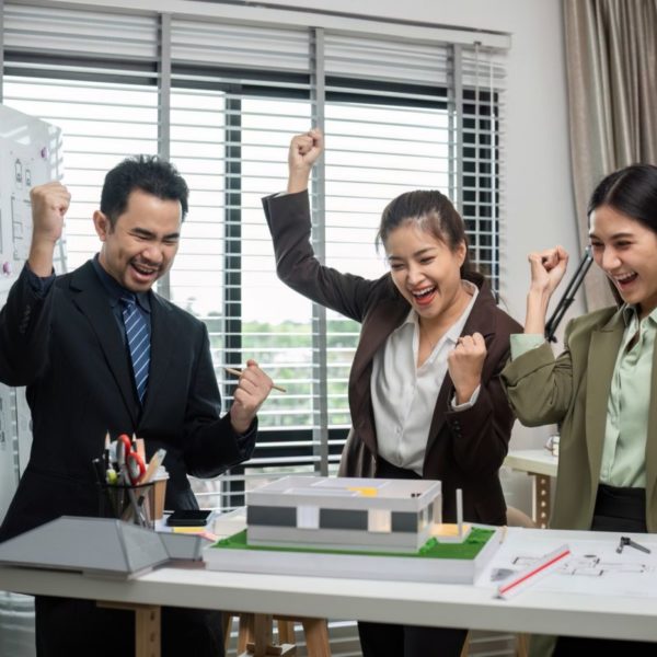 Happy Business Team Celebrates Successful Real Estate Project Completion in Modern Office