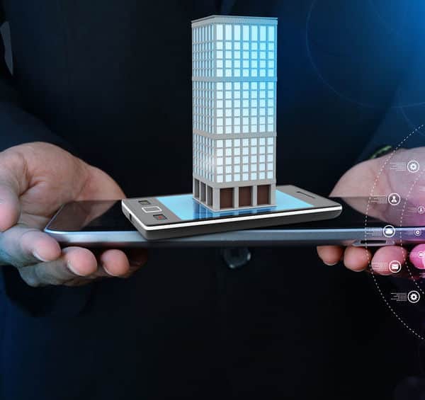Une Personne Tient Une Tablette Et Un Smartphone, Affichant Un Modèle Numérique 3d D'un Bâtiment, Avec Des Graphiques Numériques Qui Les Entourent.