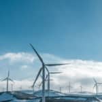 Des éoliennes Sur Des Collines Enneigées Sous Un Ciel Bleu Clair, Générant De L'énergie Renouvelable.