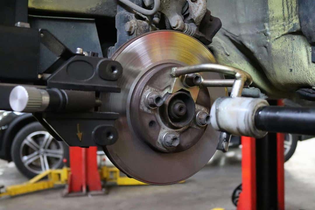Gros Plan D'un Ensemble De Freins à Disque De Voiture Avec Des Conduites De Frein Attachées Et Des Composants De Suspension Environnants Dans Un Atelier.