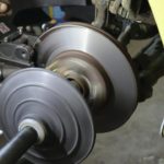 Une Machine Est Utilisée Pour Refaire La Surface D'un Disque De Frein De Voiture, Le Disque Tournant Rapidement Lorsqu'il Est Fixé à Un Véhicule Jaune.