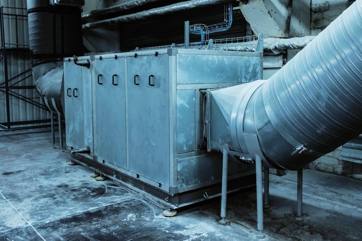 Grande Unité Industrielle De Ventilation Ou De Cvc Avec Des Conduits Métalliques Raccordés Dans Une Installation Intérieure, Entourée D'un Sol Et De Murs En Béton.
