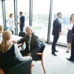 Plusieurs Professionnels Sont Engagés Dans Des Conversations Et Des Réunions Dans Un Bureau Moderne Et Lumineux Doté De Grandes Fenêtres.