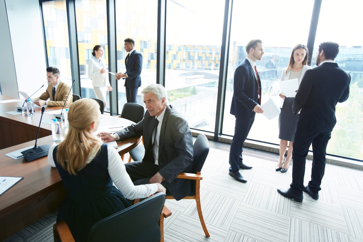Plusieurs Professionnels Sont Engagés Dans Des Conversations Et Des Réunions Dans Un Bureau Moderne Et Lumineux Doté De Grandes Fenêtres.