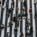 Vue Aérienne De Nombreuses Personnes Traversant Un Large Passage Piéton Rayé Noir Et Blanc Dans Une Rue De La Ville.