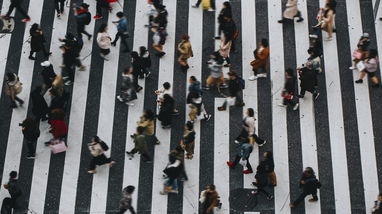 Vue Aérienne De Nombreuses Personnes Traversant Un Large Passage Piéton Rayé Noir Et Blanc Dans Une Rue De La Ville.