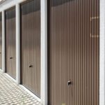 Une Rangée De Portes De Garage Brunes Fermées Avec Un Trottoir à Motifs Devant, Idéal Pour Ceux Qui Recherchent Une Solution Garde Meuble Sécurisé Angers.