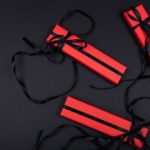 Quatre Boîtes Rectangulaires Rouges Avec Des Rubans Noirs Sont Disposées Sur Une Surface Noire, Avec Quelques Brins De Rubans Enroulés Autour Des Boîtes.